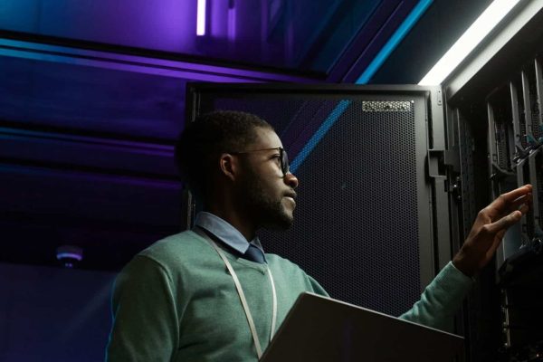 Techniker mit Brille und Laptop am Serverrack im Rechenzentrum für Otis Robust Schwerlastaufzüge.