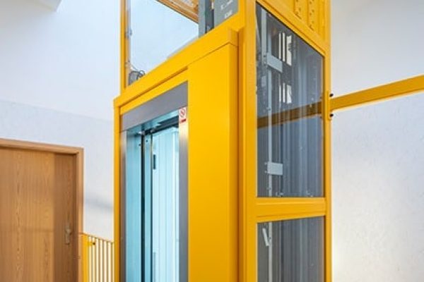 Gelber Gen2 Flex+ Aufzug im hellen Treppenhaus der Wohnungsgenossenschaft Schmalkalden eG.