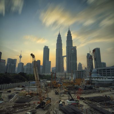Großbaustelle mit Kränen vor Stadt-Skyline