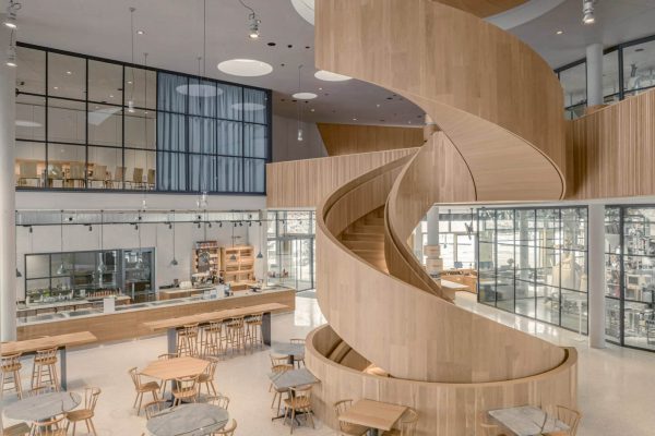 Moderne Vollholz-Spiraltreppe im lichtdurchfluteten Innenraum des Rapunzel Besucherzentrums in Legau.