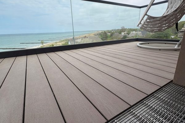 ACO Profiline Entwässerungsrinne am barrierefreien Übergang eines Balkons mit Holzdeck und weitem Meerblick.