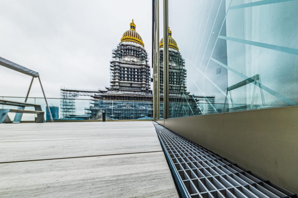 Fassadenentwässerungsrinne auf einer Dachterrasse mit Blick auf ein eingerüstetes Kuppelgebäude in Brüssel.