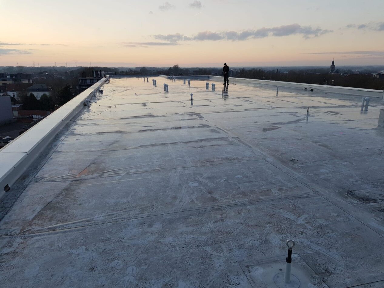 Großflächiges Flachdach mit installierter Abdichtungsbahn während der Bauphase eines Gewerbegebäudes.