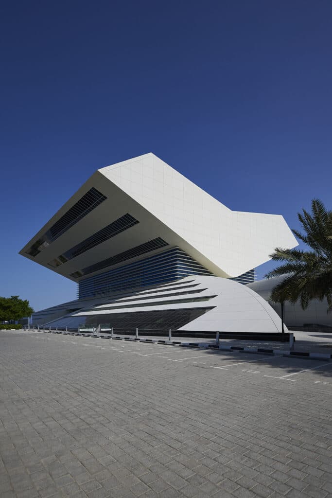 Außenansicht der Mohammed Bin Rashid Library in Dubai mit markanter geometrischer Dachform und klarer Linienführung vor tiefblauem Himmel.
