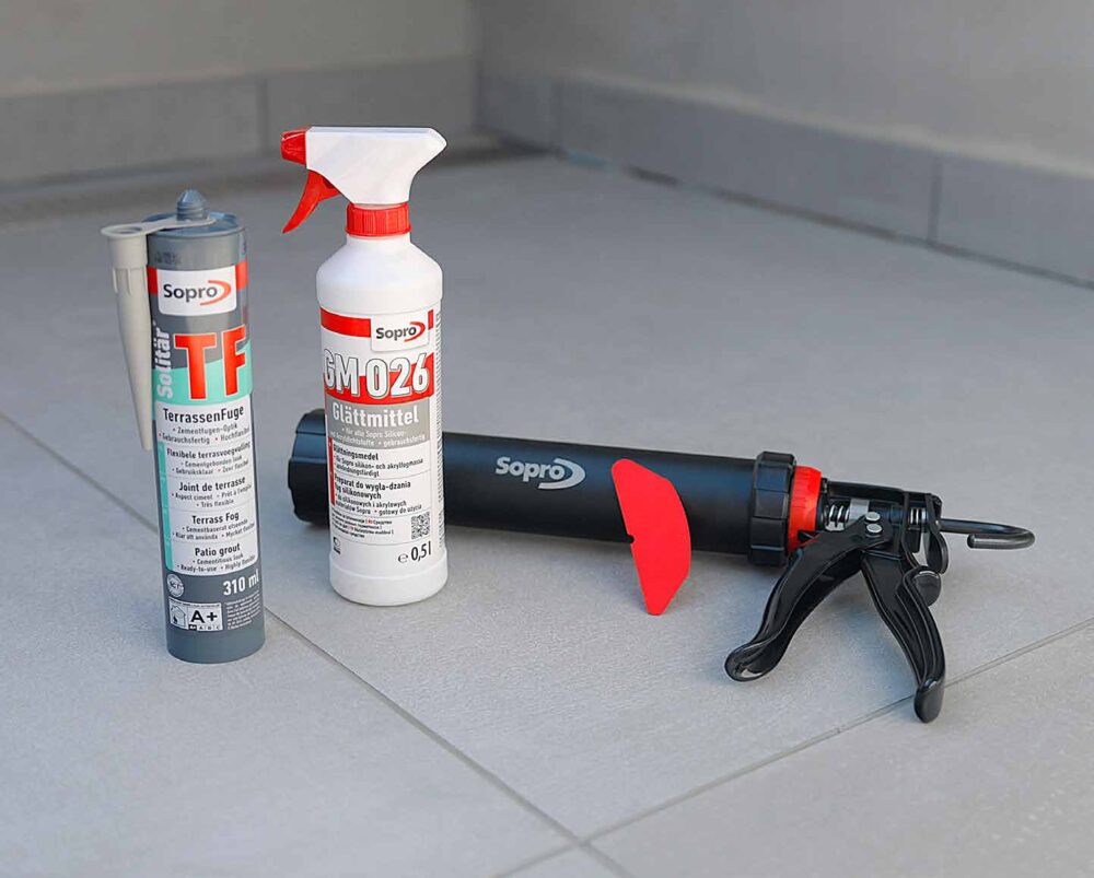 Sopro Terrassenfuge TF, Glättmittel GM026 und Kartuschenpistole auf gefliestem Boden.