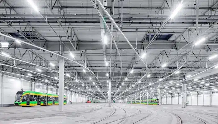 Innenansicht eines großen Straßenbahndepots mit Schienen und heller LED-Hallenbeleuchtung für optimale Ausleuchtung.