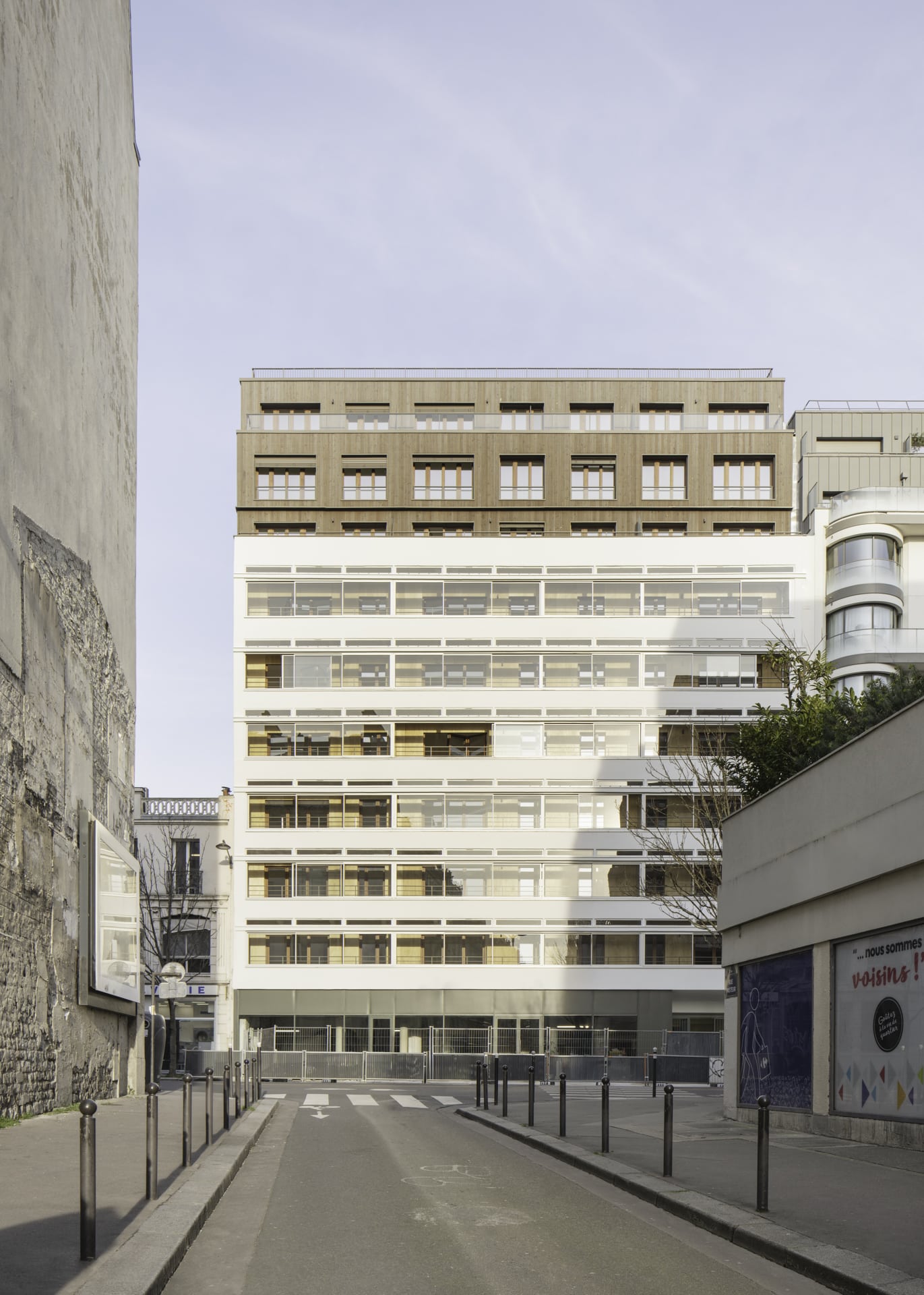 Fassade eines Pariser Mehrgeschossbaus mit markanten Glas-Faltwänden und modernem Holzaufbau.