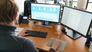Ingenieur arbeitet am Computer an der Planung von Vakuum-Isolationslösungen mit zwei Bildschirmen.