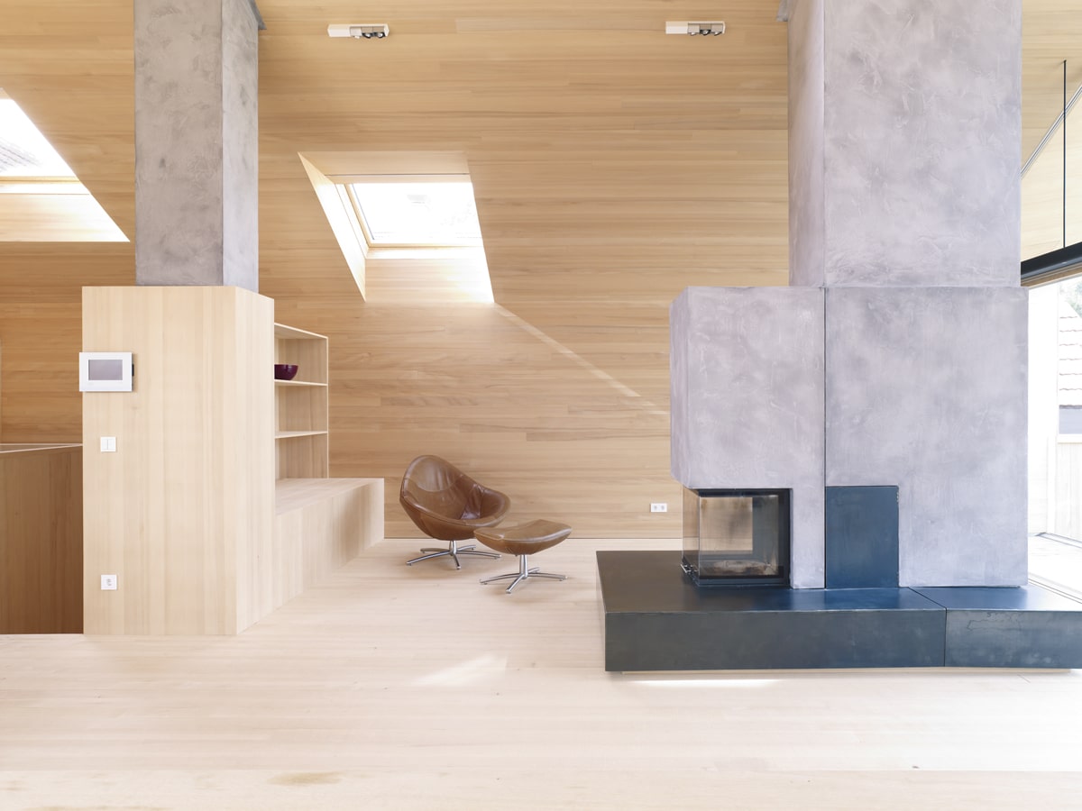 Wohnraum unter dem Dach mit Kamin, Holzverkleidung und Lichteinfall durch Dachfenster.