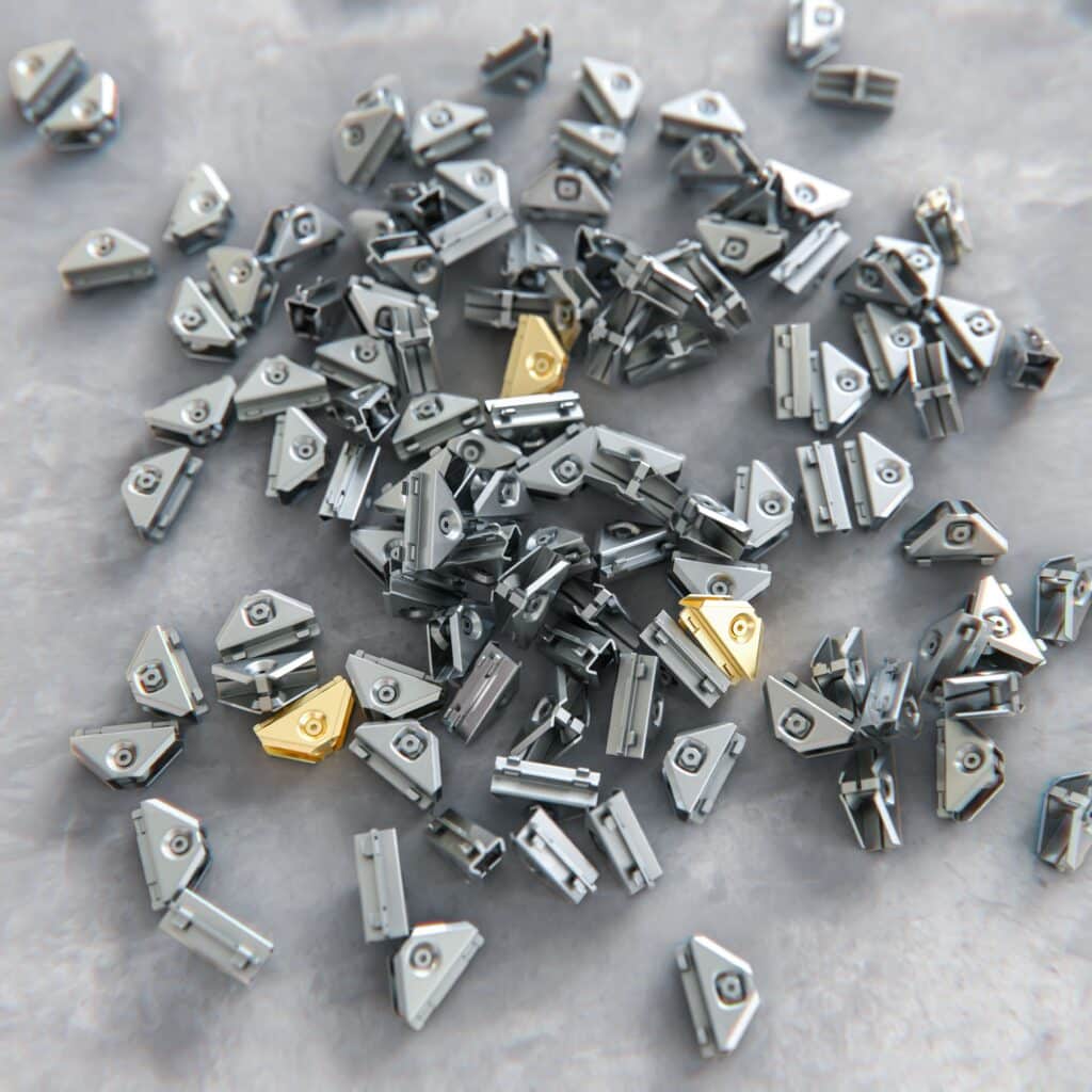 Nahaufnahme mehrerer TECEprofil Eckverbinder aus Metall, mit einzelnen goldfarbenen Elementen für die Vorwandinstallation.