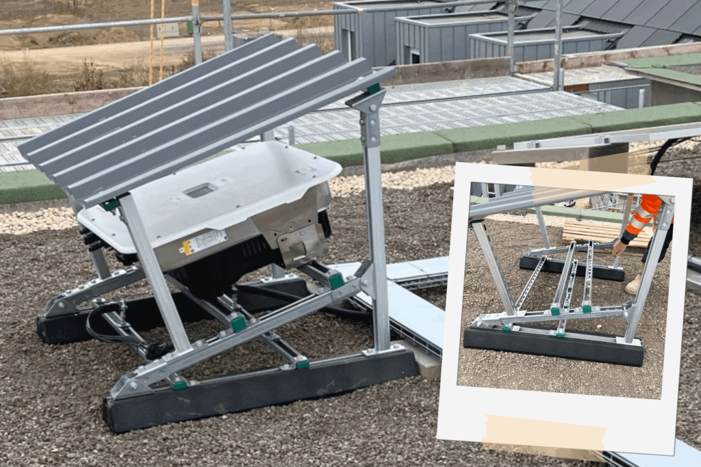 Montierte Wechselrichter-Unterkonstruktion auf einem Kies-Flachdach, bestehend aus einem verzinkten Metallgestell mit Ballastierung; dahinter technische Aufbauten und Dachlandschaft