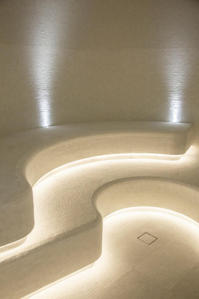 Heller Wellnessraum mit geschwungenen Sitzflächen und indirekter LED-Beleuchtung.