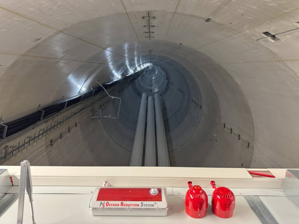 Blick nach oben in den Innenraum eines Windradturms mit Kabeltrassen und Aufstiegsleitern.