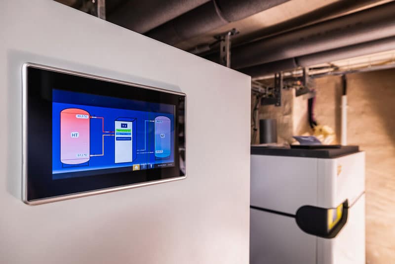 Nahaufnahme eines Steuerungsdisplays einer Wärmepumpe im Heizraum, das den HT- und NT-Kreislauf grafisch zeigt.